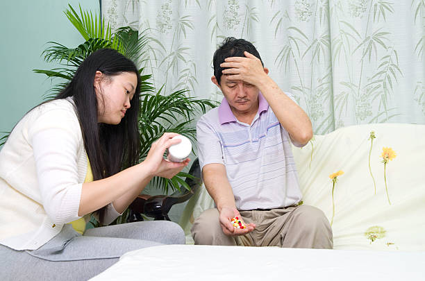 Asian man having medicine at home. Daughter take care of her father. hypnothérapeute remboursé Lyon